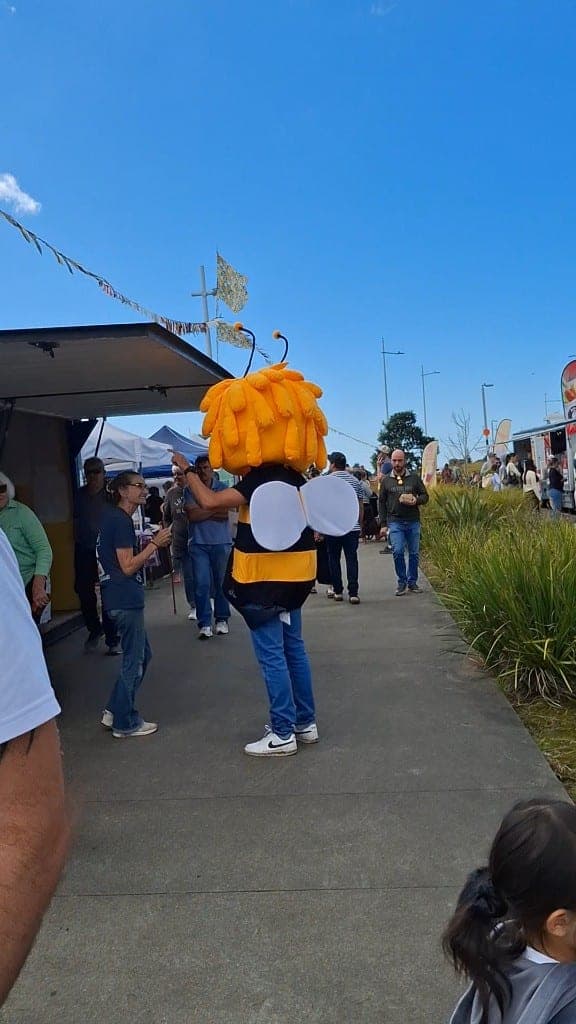 The bee mascot mingling with families and their dogs at the market